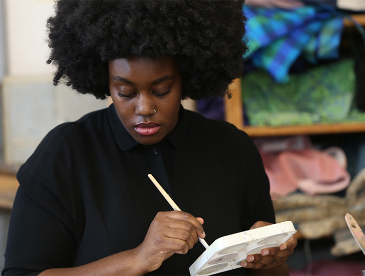 student painting at desk in art studio