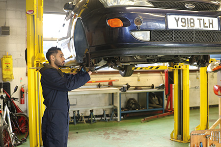 Student looking at the underneath of a car